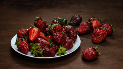 Fresh strawberries in ceramic bowl on dark wooden background. Selective focus. - Image