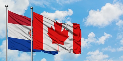 Paraguay and Canada flag waving in the wind against white cloudy blue sky together. Diplomacy concept, international relations.