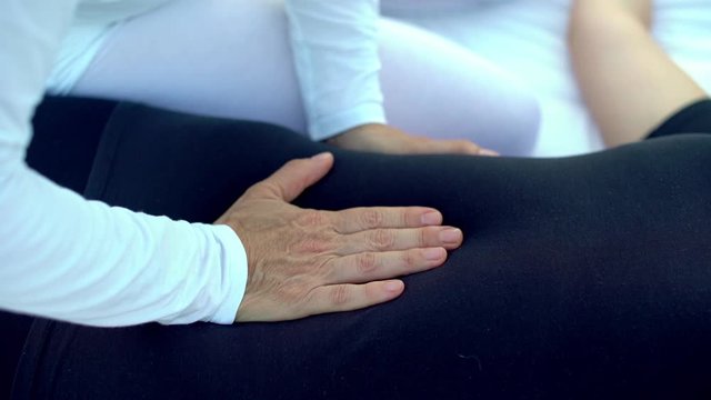 Shiatsu massage, shiatsu treatment. Closeup of hands of a masseuse pressing and massaging stomach tummy and Hara of a woman. Healthy care for wellness and wellbeing.