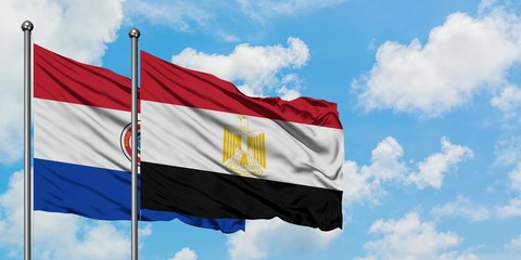 Paraguay and Egypt flag waving in the wind against white cloudy blue sky together. Diplomacy concept, international relations.
