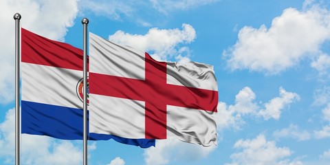 Paraguay and England flag waving in the wind against white cloudy blue sky together. Diplomacy concept, international relations.