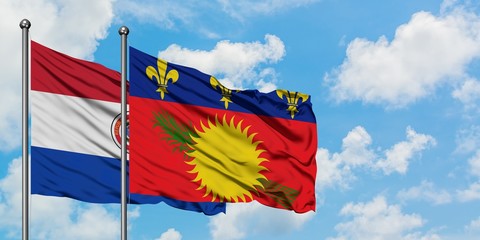 Paraguay and Guadeloupe flag waving in the wind against white cloudy blue sky together. Diplomacy concept, international relations.
