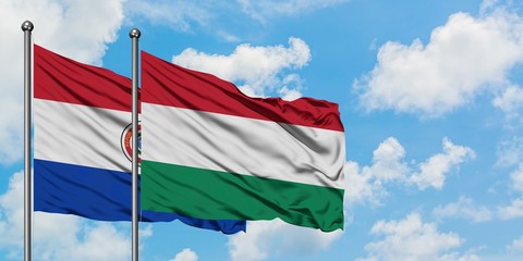 Paraguay and Hungary flag waving in the wind against white cloudy blue sky together. Diplomacy concept, international relations.