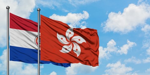 Paraguay and Hong Kong flag waving in the wind against white cloudy blue sky together. Diplomacy concept, international relations.