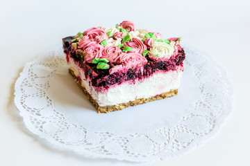 Delicious floral cherry cheesecake slice decorated with creamy colorful flowers on white background.