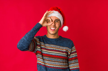 Young man on christmas day has friendly expression, pressing palm to chest. Love concept.