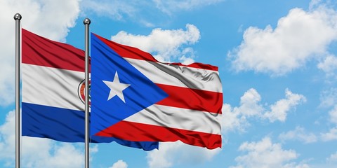 Paraguay and Puerto Rico flag waving in the wind against white cloudy blue sky together. Diplomacy concept, international relations.