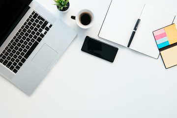 Top view of office table. White office desk table with laptop, cup of coffee and supplies.