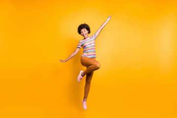 Fototapeta na wymiar Full length body size photo of cheerful positive funky ecstatic overjoyed girl in orange pants striped t-shirt footwear jumping isolated vibrant color background