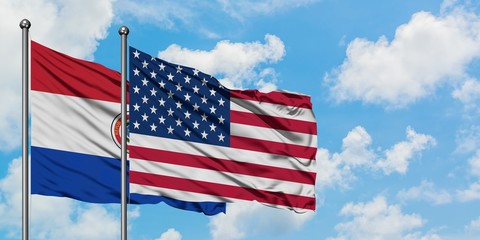 Paraguay and United States flag waving in the wind against white cloudy blue sky together. Diplomacy concept, international relations.