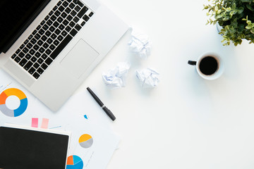 Top view of office table. White office desk table with laptop, cup of coffee and supplies.