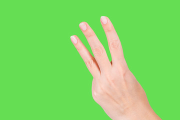 Closeup view of beautiful white manicured female hand showing three fingers up isolated on bright green background. Math and counting concept. Horizontal color photography.