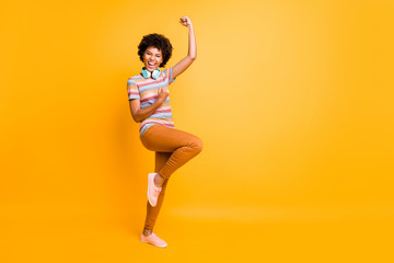 Fototapeta na wymiar Full length body size photo of cheerful victorious excited crazy girl screaming yes wearing pants trousers footwear wireless headphones isolated over yellow vivid color background