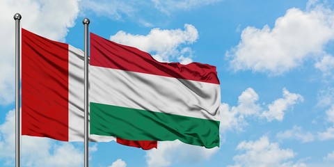 Peru and Hungary flag waving in the wind against white cloudy blue sky together. Diplomacy concept, international relations.