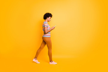 Fototapeta na wymiar Full length body size photo of pensive concentrated focused girl browsing through social media wearing orange pants trousers footwear walking isolated over vivid color background
