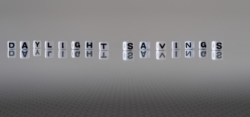 The words Daylight Savings represented by black letters on white cubes with a grey background