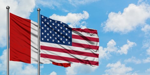 Peru and United States flag waving in the wind against white cloudy blue sky together. Diplomacy concept, international relations.