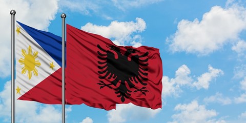 Philippines and Albania flag waving in the wind against white cloudy blue sky together. Diplomacy concept, international relations.