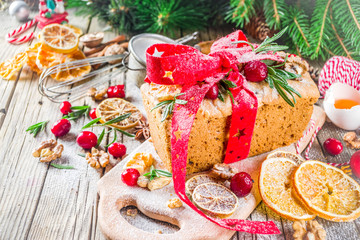 Obraz na płótnie Canvas Traditional Christmas and winter holidays baking. Fruit cake with icing, nuts, berry dry orange and rosemary. Sweet homebaked cake on old wooden background with Christmas decoration