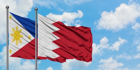 Philippines and Bahrain flag waving in the wind against white cloudy blue sky together. Diplomacy concept, international relations.