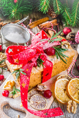 Traditional Christmas and winter holidays baking. Fruit cake with icing, nuts, berry dry orange and rosemary. Sweet homebaked cake on old wooden background with Christmas decoration