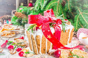 Traditional Christmas and winter holidays baking. Fruit cake with icing, nuts, berry dry orange and rosemary. Sweet homebaked cake on old wooden background with Christmas decoration