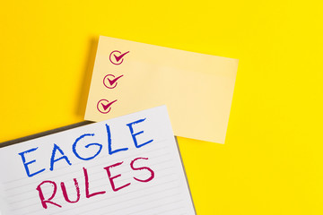 Conceptual hand writing showing Eagle Rules. Concept meaning a huge set of design rules which your layout needs to pass Empty orange paper with copy space on the yellow table