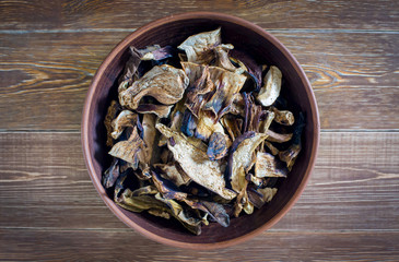 Sliced dried mushrooms lie in a clay plate close-up, top view