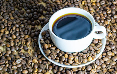 a cup of coffee with cookies, coffee grains scattered on a table near a cup with a coffee