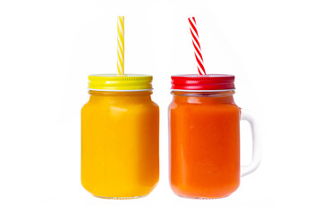Two closeup glass jars of orange and yellow color smoothies with mango and papaya isolated at white background. Concept of healthy vegan food
