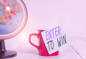Conceptual hand writing showing Enter To Win. Concept meaning exchanging something value for prize or chance of winning Globe map coffee cup sticky note lying vintage wooden table