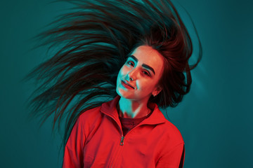 Photo in motion. Nice hair. Studio shot indoors with neon light. Portrait of beautiful young girl