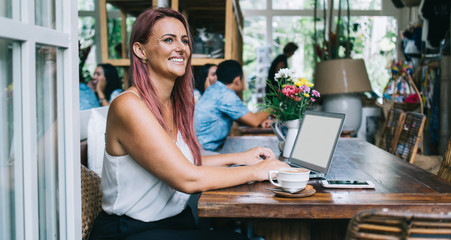 Happy freelancer using laptop with empty screen in cafe