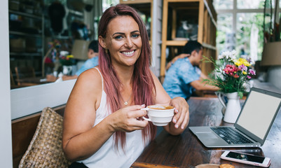 Friendly woman enjoying latte in restaurant