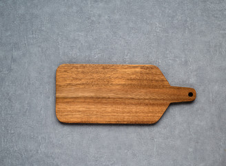 Wooden cutting board on gray concrete background. Table top view and copy space for text. Restaurant menu, recipe, food background mock up. Copy space