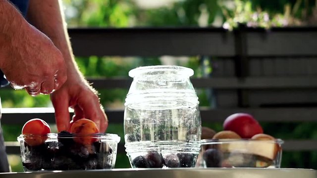Hand adding fruits to the jar, super slow motion