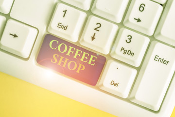 Conceptual hand writing showing Coffee Shop. Concept meaning small informal restaurant serving coffee and light refreshments White pc keyboard with note paper above the white background