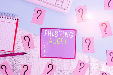 Handwriting text Phishing Alert. Conceptual photo aware to fraudulent attempt to obtain sensitive information Writing tools, computer stuff and math book sheet on top of wooden table