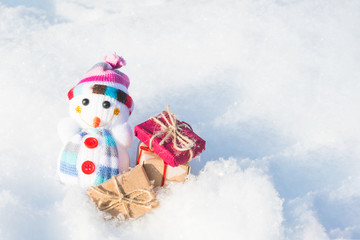 toy snowman with gifts in the snow