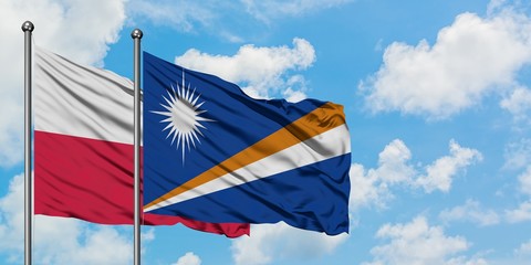 Poland and Marshall Islands flag waving in the wind against white cloudy blue sky together. Diplomacy concept, international relations.