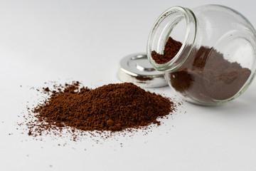 Glass jar with ground coffee upside down. Rashes ground coffee from a jar on a white background.