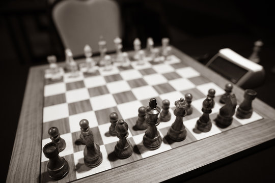 Monochrome shallow depth of field (selective focus) image with wooden chess pieces on a wooden table before a professional competition.