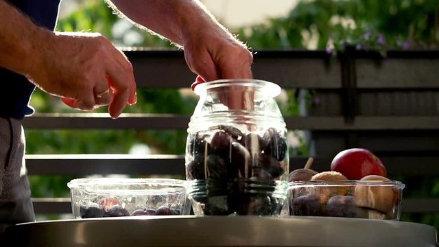Hand adding fruits and seasoning to the jar, super slow motion