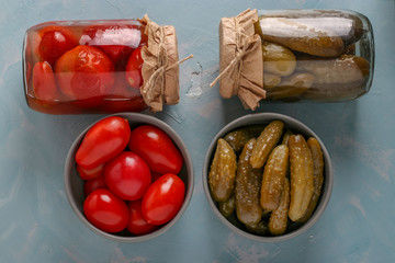 Homemade salted tomatoes and cucumbers in a bowls and a glass jars on a light blue background, Concept Fermented Vegetables