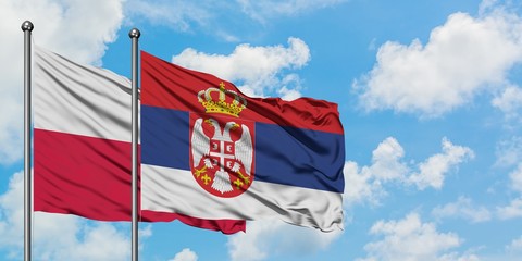 Poland and Serbia flag waving in the wind against white cloudy blue sky together. Diplomacy concept, international relations.