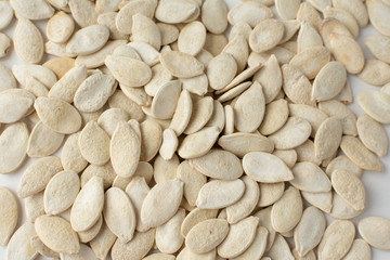 Roasted pumpkin seeds with salt on white background.