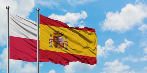 Poland and Spain flag waving in the wind against white cloudy blue sky together. Diplomacy concept, international relations.