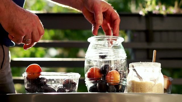 Hand adding fruits to the jar, super slow motion