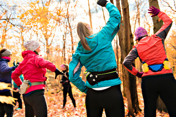 woman group out running together in an autumn park they run a race or train in a healthy outdoors lifestyle concept
