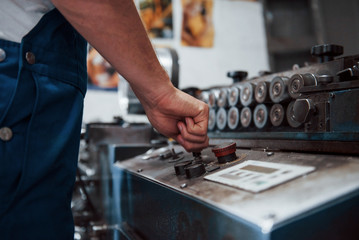 Turns on the machine. Man in uniform works on the production. Industrial modern technology